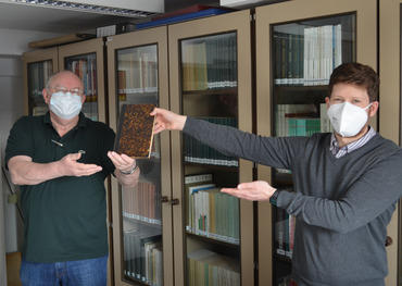 Peter Nettekoven (links) überreicht Stadtarchivar Jens Löffler ein Buch zur Stadtgeschichte