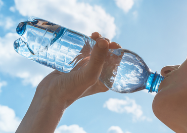 Frau trinkt Wasser an heißem Sommertag