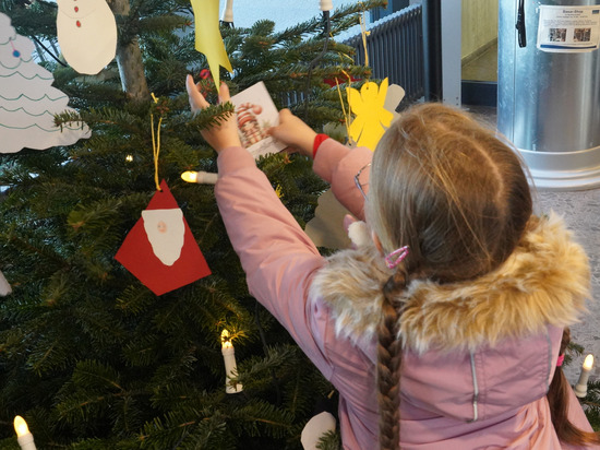 Schulkinder schmücken den Weihnachtswunschbaum Schulkinder schmücken den Weihnachtswunschbaum
