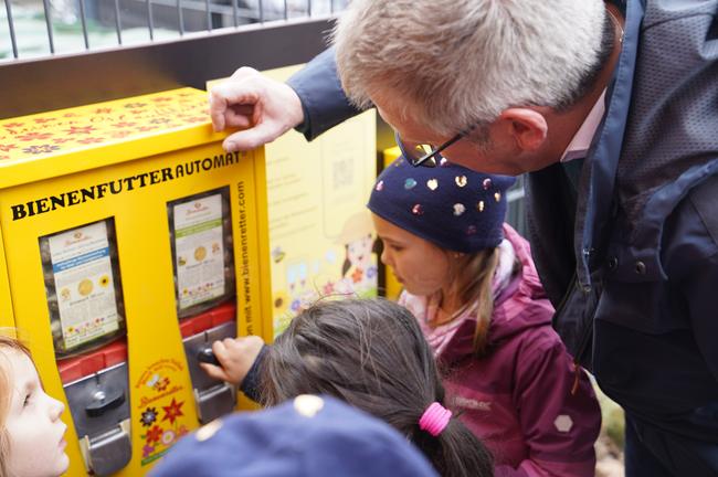 Bürgermeister Christoph Becker und Kita-Kinder am Bienenfutterautomaten