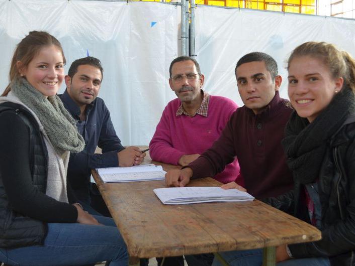 Die Schülerinnen Lea Schmitz (18) (links auf der Bank) und Miriam Fontes (17) geben den Flüchtlingen Deutschunterricht. 