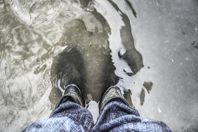 Mann bei Unwetter in Gummistiefeln