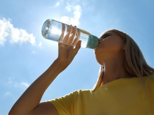 Frau trinkt Wasser bei Hitze